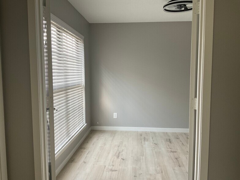 The second bedroom featuring large windows, walk-in closet, LED ceiling fan, and hardwood flooring - 12743 W 110th Ter