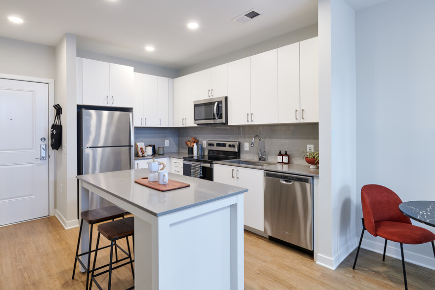 Design Collection II kitchen with white cabinetry, grey tile backsplash, grey quartz countertops, and stainless steel appliances - Avalon Foundry Row