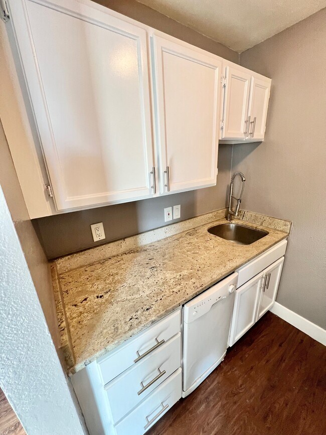 Experience the elegance of this kitchen, featuring pristine white cabinetry and luxurious granite surfaces. - Williams Street