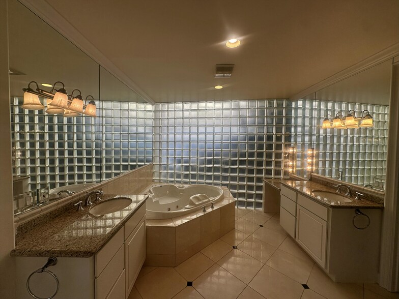 Luxurious primary bathroom featuring a Jacuzzi tub enclosed in glass block walls, 2 vanities - 8120 Billowvista Dr