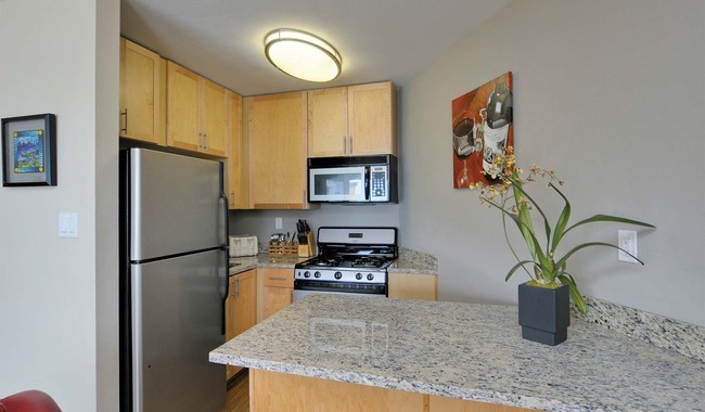 Bright and open kitchen with granite countertops and breakfast bar - The Bluffs at Pacifica Apartments