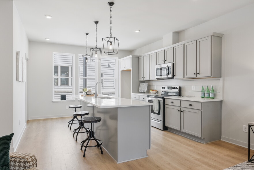 The kitchen blends form and function—quartz countertops, soft-close cabinetry and designer lighting. - 358 E Village Ln
