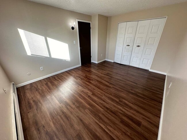 Experience comfort and tranquility in this airy bedroom with stylish wood floors. - Country Club