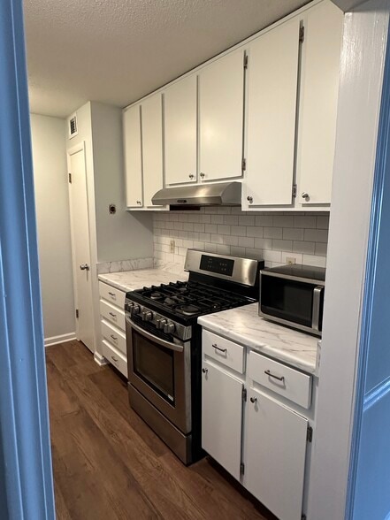 Renovated kitchen: Pantry, tiled backsplash, oven, gas stove, and microwave. - 1177 Church St