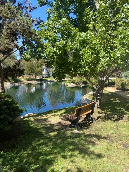 Shaded seating beside the landscaped lake - 8305 Summertime Ln