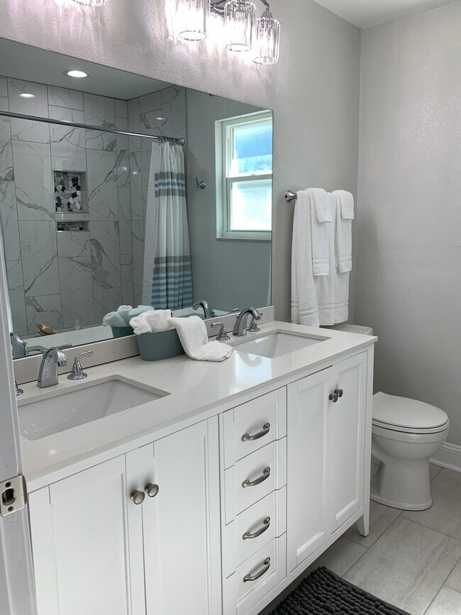 Hall bathroom with double vanity, tub with shower. - 1301 E Leonard St