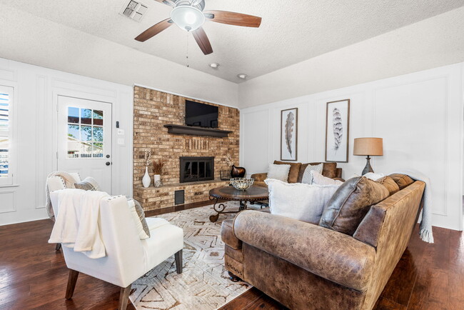 Living room featuring a brick, wood burning fireplace and ceiling fan. - 209 Prairie Wind Blvd