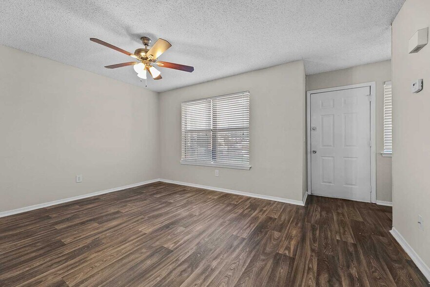 Vacant bedroom with dark wood-look vinyl flooring, ceiling fan with light, window with blinds, and white closet door - Walnut Creek at 122