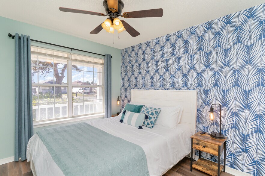 A queen-size bed with A 50" Roku TV, a ceiling fan, 2 lamps and a blackout curtains, nightstands. - 6464 Starfish Cv