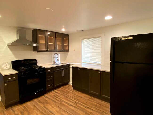 Newer kitchen with overhead vent, modern faucet and newer cabinets - 1928 N Monticello Ave