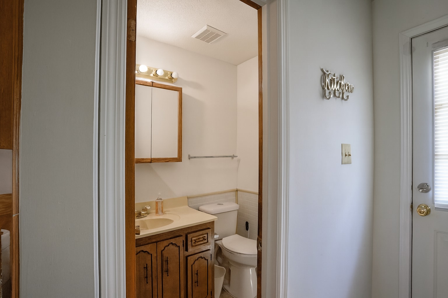 Half bath near kitchen with updated lighting, classic vanity, and neutral tones. - 2313 Salem West Dr
