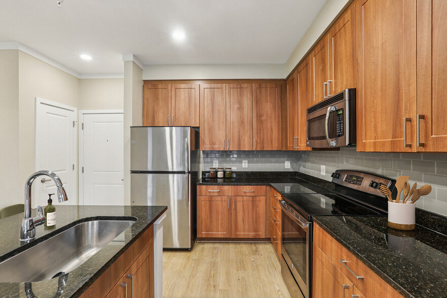 Updated Finishes kitchen with stainless steel appliances, grey tile backsplash, granite countertops, and new hard surface flooring and lighting - Avalon Falls Church