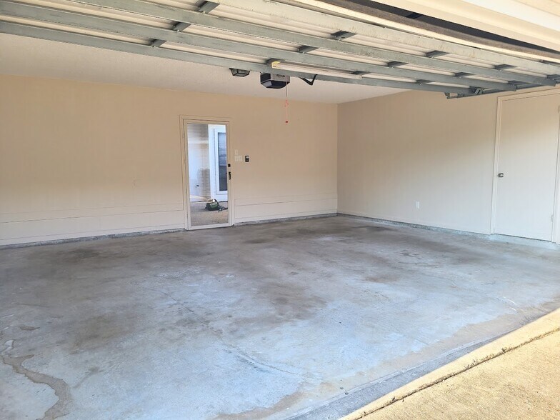 Enclosed 2-car garage includes large utility room and door leading to private patio - 12439 Coursey Blvd