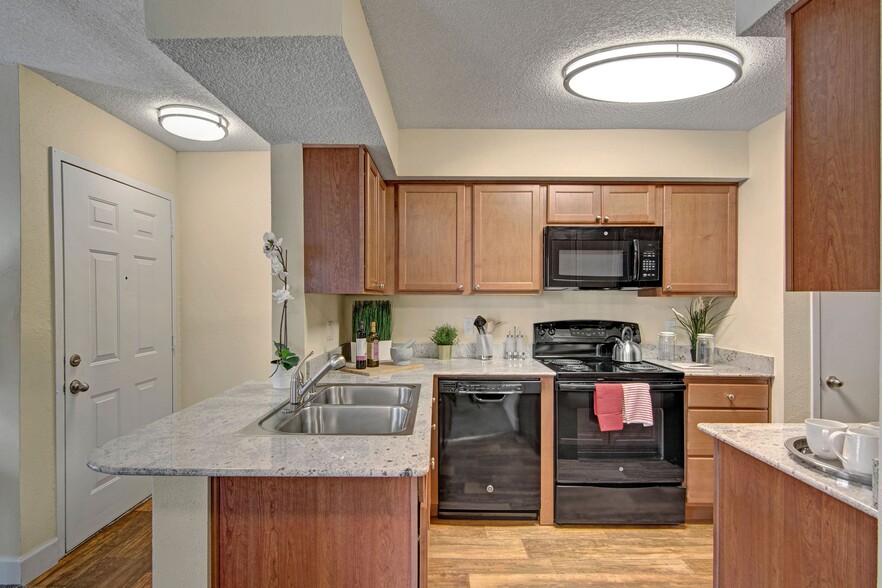 A kitchen with light cabinets and black appliances - Motif