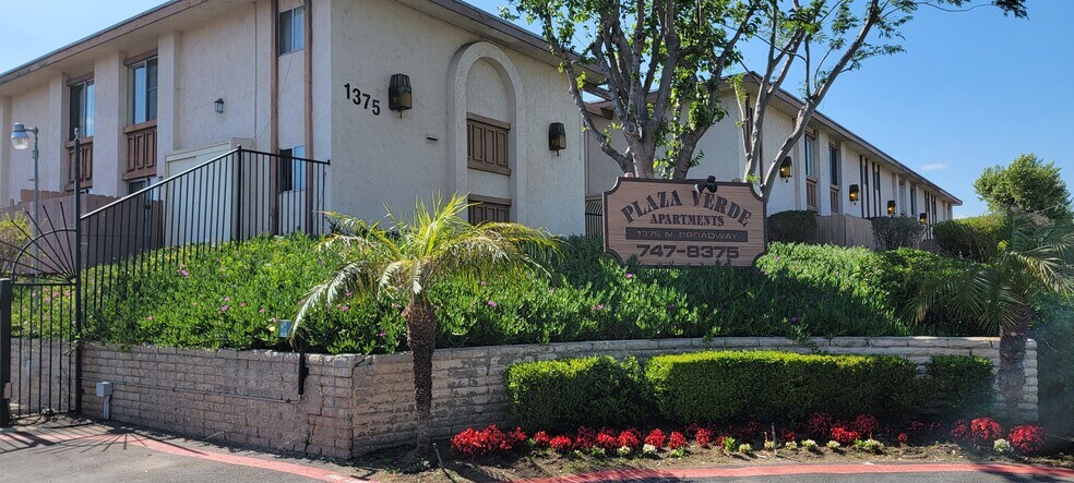 Gated front enterance with lush gardens at Plaza Verde Apartments in Escondido, California. - Plaza Verde