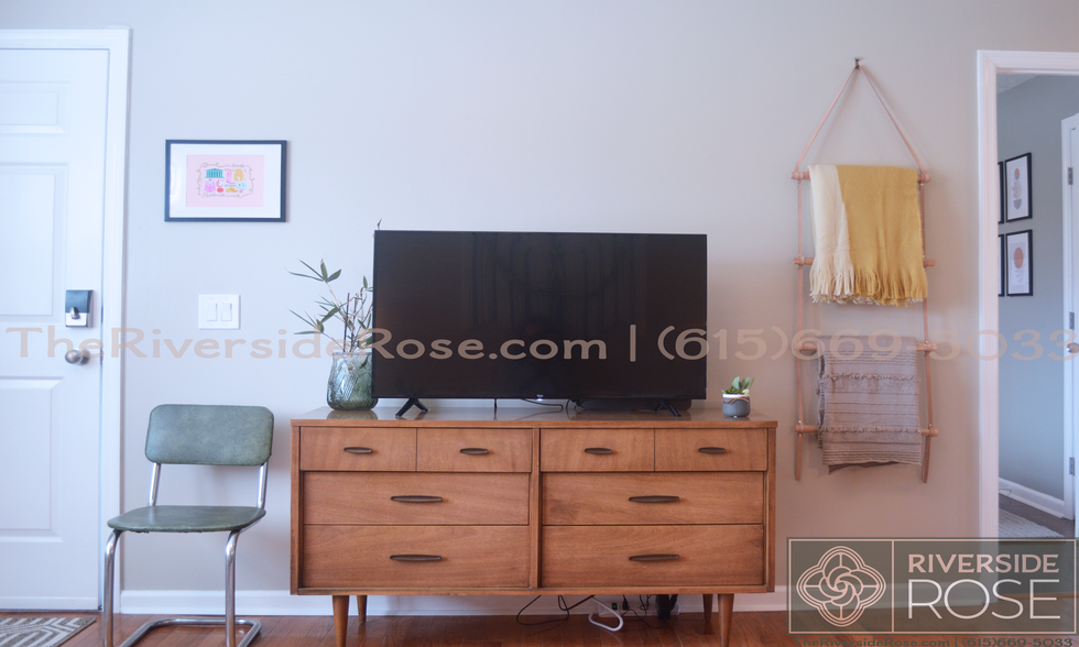 Smart TV sitting on a vintage mid-century dresser. Extra blankets hanging on a wall ladder - 3726 Moss Rose Dr