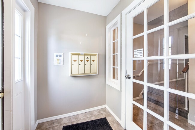 Bright apartment entryway featuring mailboxes and control access entry door, offering a welcoming and secure entrance. - Woods Mill Park Apartments & Townhomes