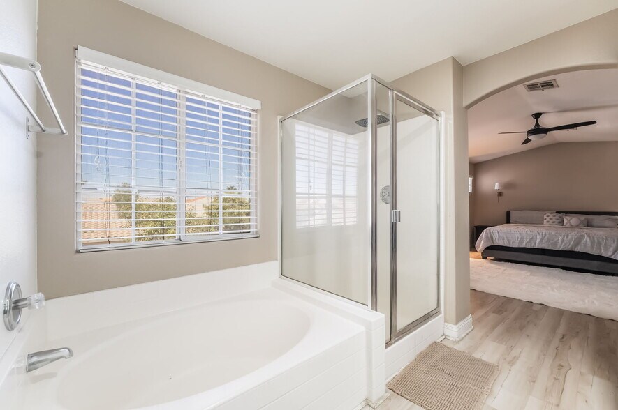 Ensuite bathroom with a stall shower, a bath, a ceiling fan, and light wood-type flooring - 1179 Antoinette St