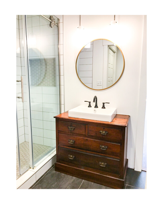 Beautiful bathroom vanity with lots of cabinet space for toiletries, big sink, and stylish modern mirror with hanging lights. - 18 W State St