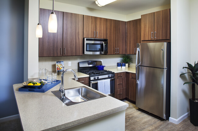 Classic Kitchen with chocolate pecan cabinetry, tile backsplash, laminate countertops, hard surface flooring, and stainless steel appliances - Avalon Framingham