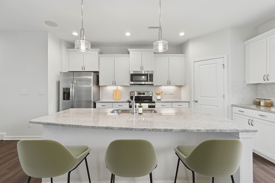 Upgrade Package kitchen with white cabinetry, designer tile backsplash and undercabinet lighting, and granite countertops - Avalon Townhome Collection Brier Creek