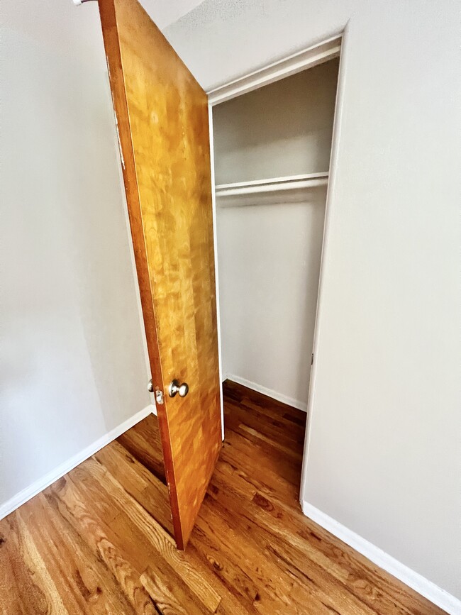 Spacious closet with polished wooden flooring, perfect for stylish storage solutions. - The Birney Apartments