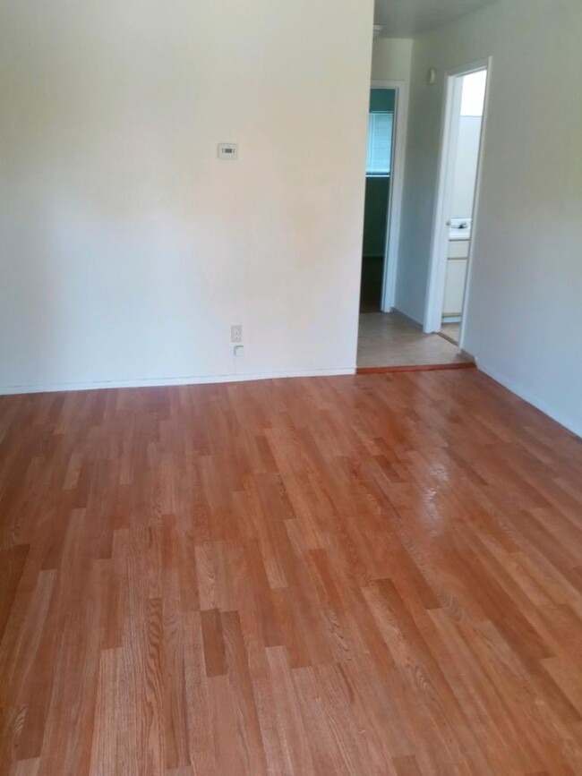 Wood plank and ceramic flooring with hall leading into carpeted bedrooms for quiet and comfort - 120 Lazy Ln