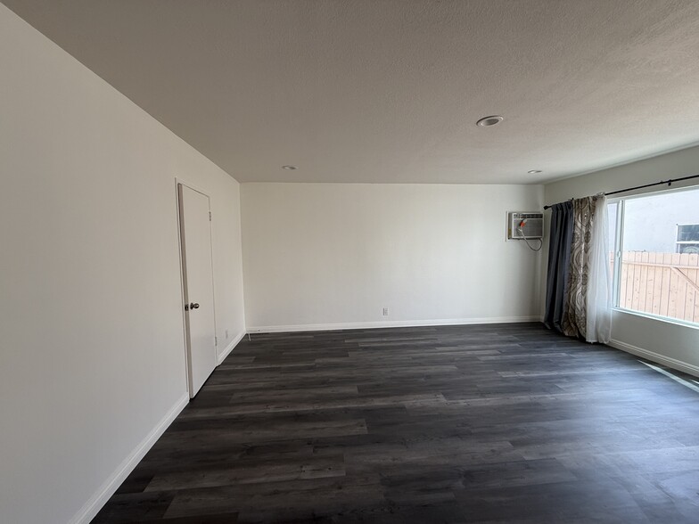 Large living room with new floors and paint and ample natural light with large windows. - 5462 Barton Ave