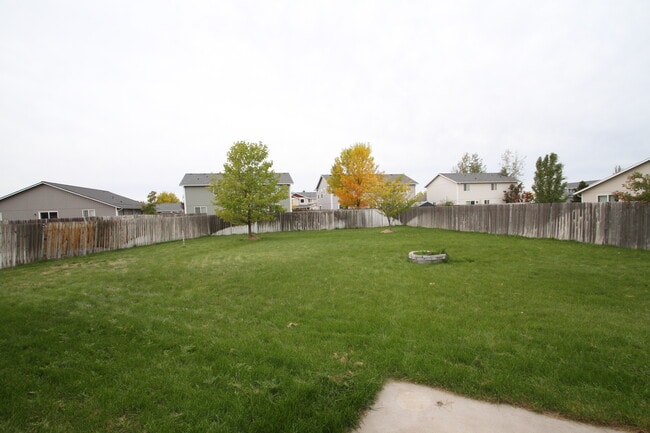 Large, fully fenced backyard with small patio and brick firepit. - 9624 Spencer Ct