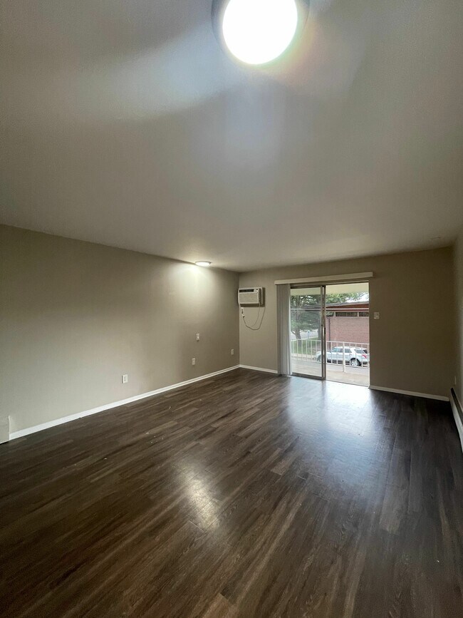 Stylish and open living room with contemporary wooden flooring, perfect for relaxation. - GRACE LANDINGS APARTMENTS
