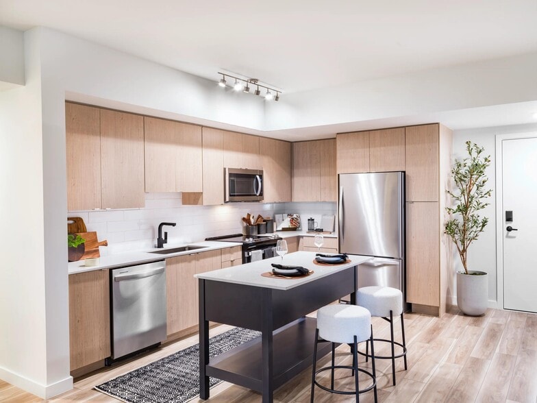 Warm wood cabinetry, clean-lined finishes, and a functional island create a kitchen designed for everyday ease at Modera Aventura. - Modera Aventura
