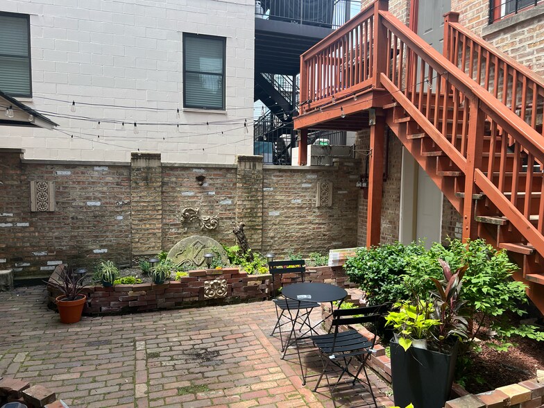 daytime view of courtyard and coach house: the white door to the unit is underneath the red stairs - 2446 W Thomas St