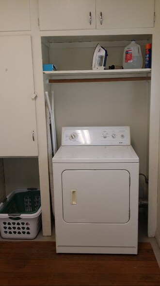 Laundry room area with view of electric dryer (ironing board, laundry baskets and other items on shelf not included with rental - 607 Harrison Ave