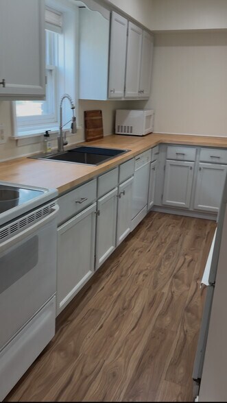 Bright galley kitchen with butcher block counters, modern faucet, full appliances, and natural light - 328 N Allen St