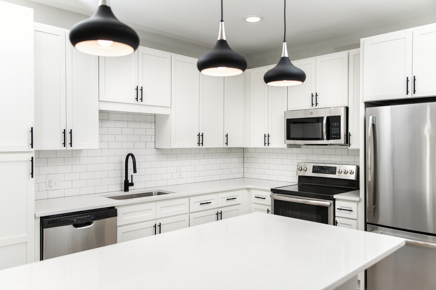 Kitchen with white quartz countertops, white cabinetry, and stainless steel appliances - Avalon South End