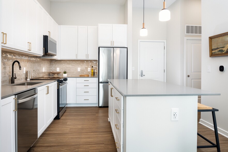 Design Collection I kitchen with white cabinetry, beige tile backsplash, grey quartz countertops, pendant lighting and hard surface flooring - Avalon Annapolis