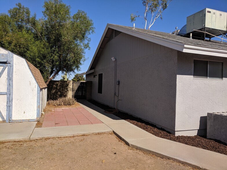 South wall of home and gate to front yard. Security light and irrigation controller in view. - 14101 N 78th Dr