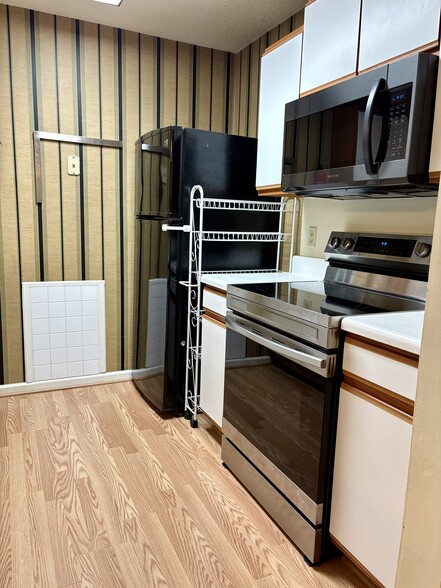 Galley kitchen with sleek stainless steel and black appliances - 208 Quarter Trl