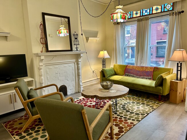 Livingroom with sofabed, lounge seating, TV, storage and built-in bookcases - 1425 N Lawrence St