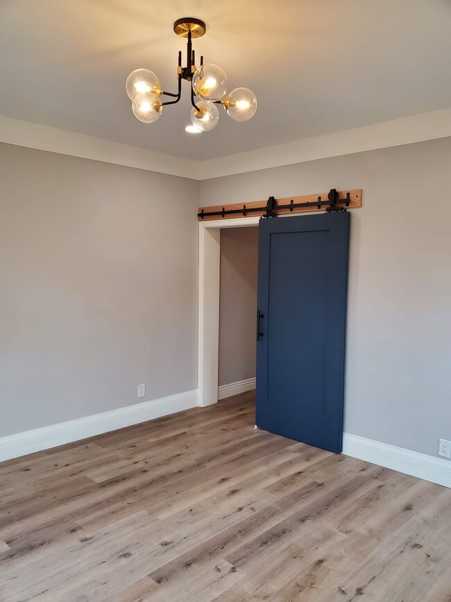 Living room with antique barn door original to property leading to hallway - 579 W. 13th St