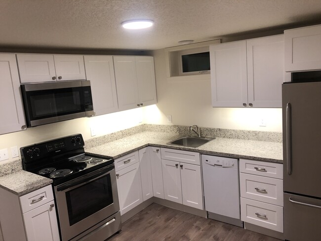 Completely renovated, full sized kitchen featuring granite counters, stainless steel appliances, dishwasher, new cabinets, LED lighting, and more. - 4842 NE Mallory Ave