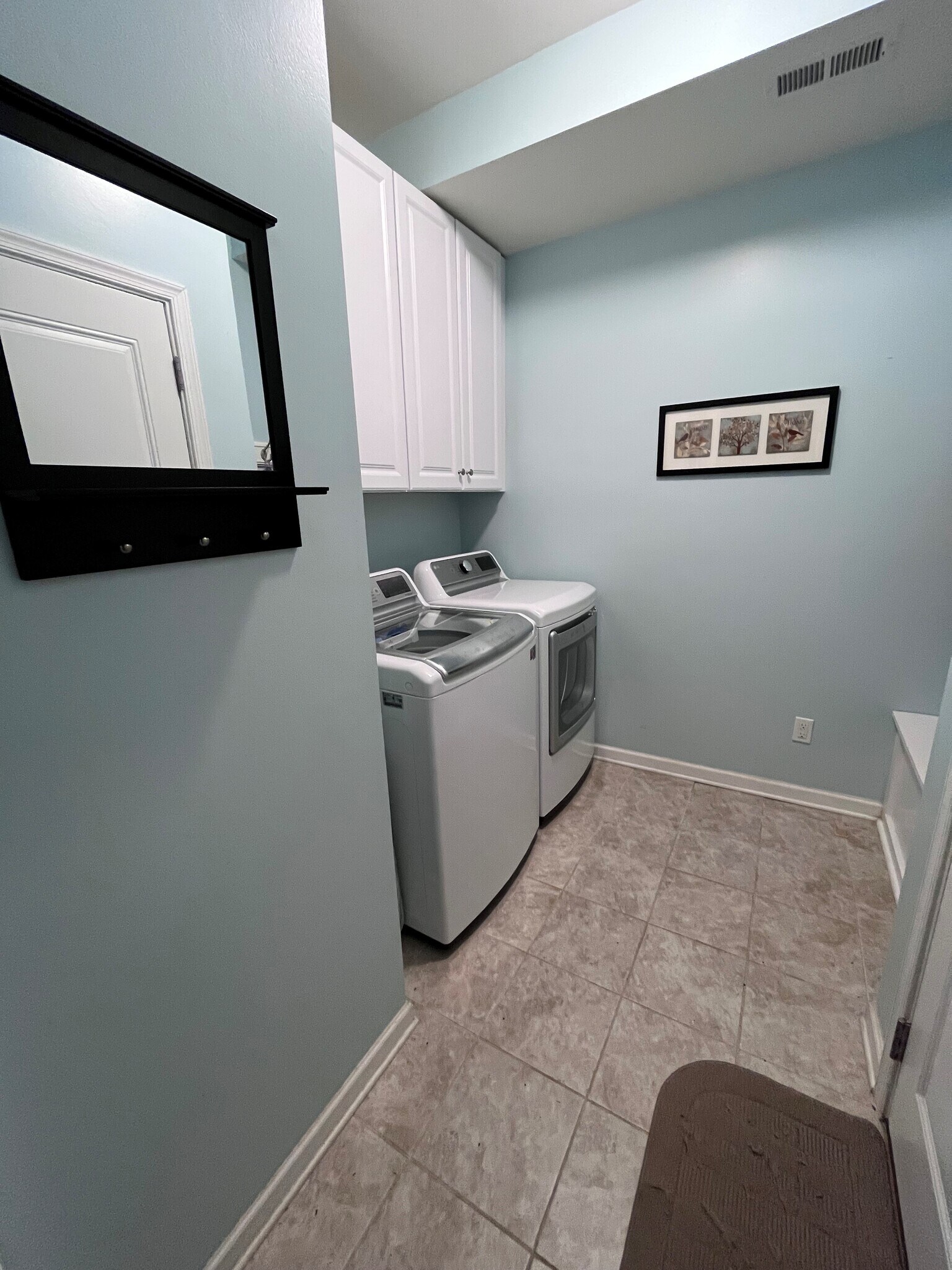 The laundry room has large cabinets above the washer & dryer for plenty of storage. - 7736 Tranquil Trl