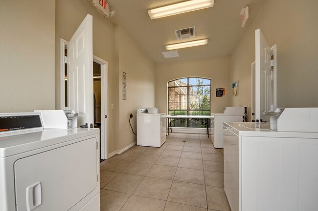 A shared laundry room with multiple washers and dryers - The Residence at Heritage Park