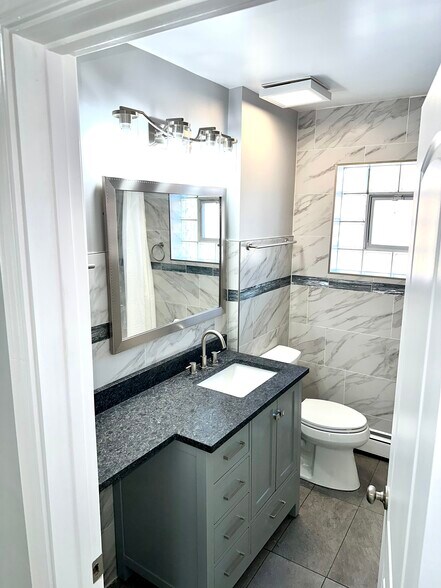 Newly redone full bath with new large counter, Kohler toilet & tiled walls & floor. - 771 56th St