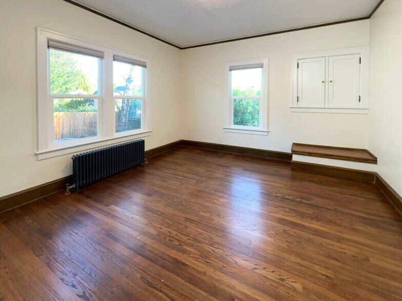 Large primary bedroom on main floor has a double closet, extra built-in cupboard, and overlooks the - 3448 SW Canby St