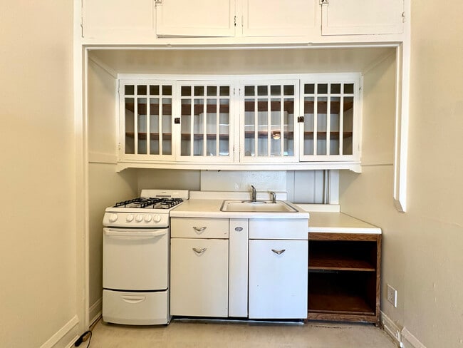 Charming vintage kitchen with built-in shelving, gas stove, and classic white cabinetry. - Ivanhoe
