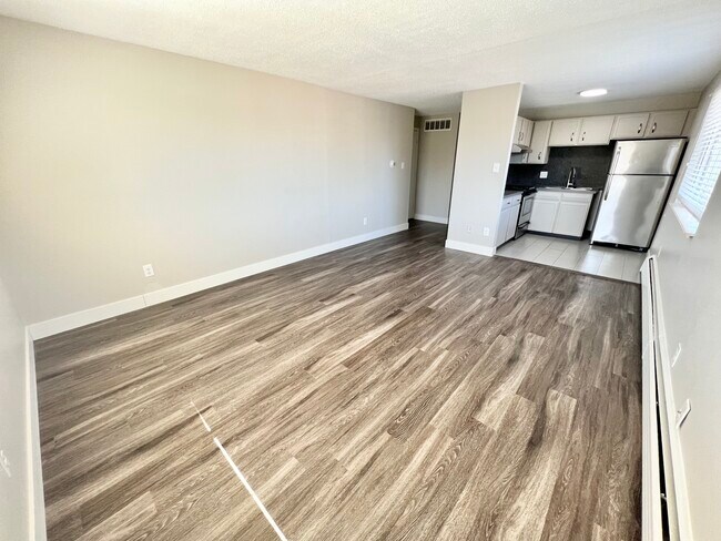 Explore this contemporary living space featuring sleek wood flooring and a compact kitchen design. - Wadsworth Station West
