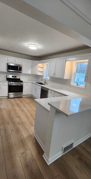 A chef-inspired kitchen defined by expansive quartz surfaces, tailored white cabinetry, and a refine - 90 E 216th St