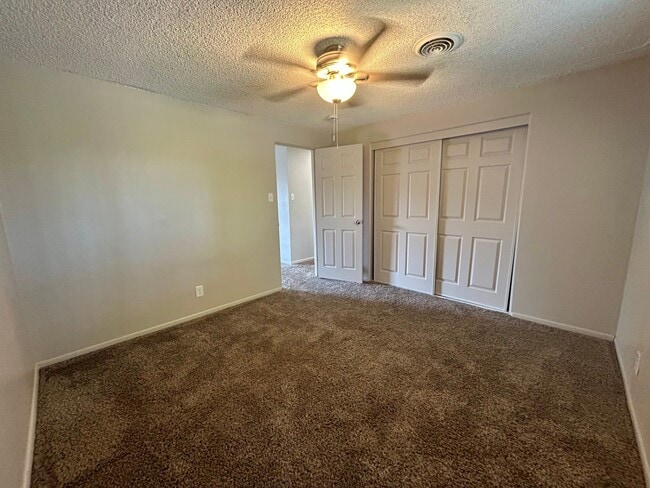 Inviting bedroom with plush carpet, ceiling fan, and ample closet space in modern apartment. - Boardwalk Apartments