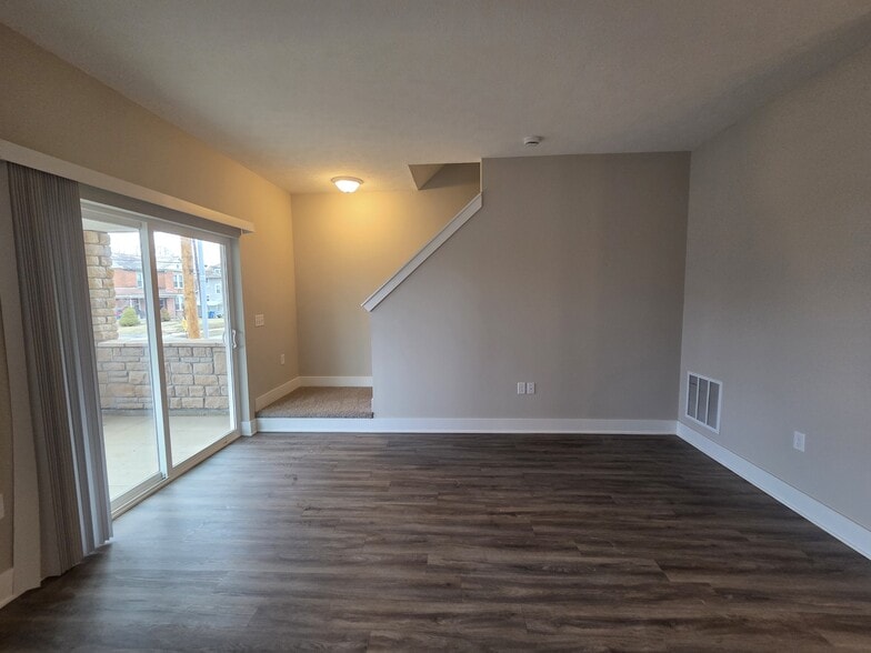 Townhome living area with walkout patio and stairs leading to second level. - Flats at Sugar Run